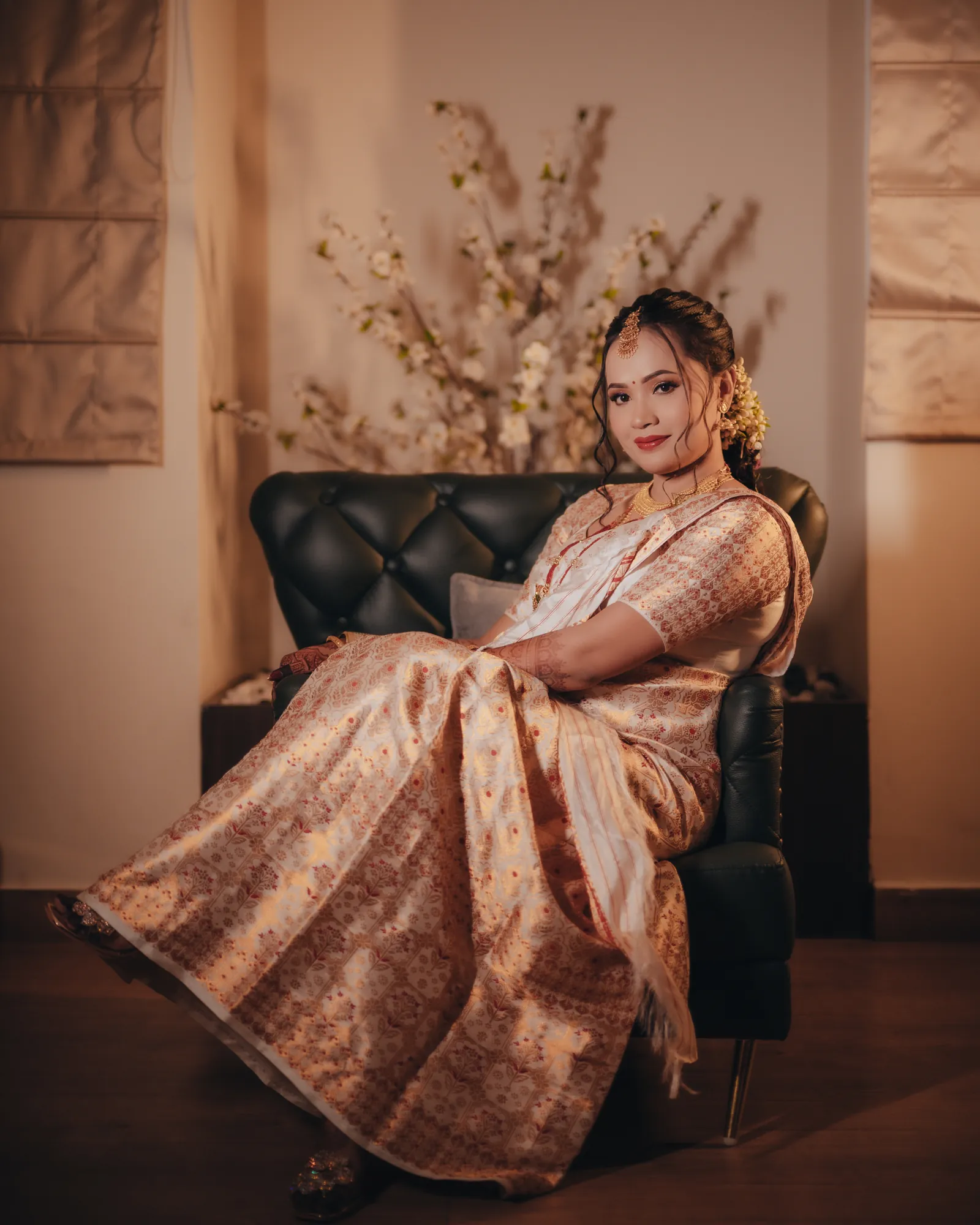 Bride in a mekhela sador seated in a leather armchair